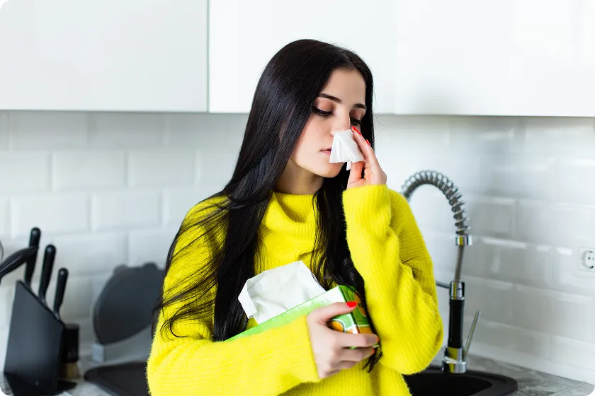 Sick woman uses a tissue in the kitchen detailing what are nasal polyps.