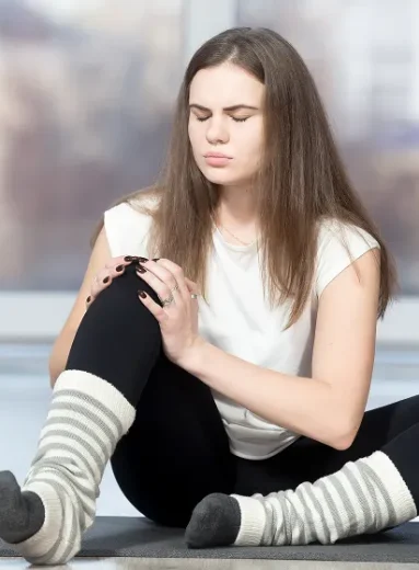 Young woman holding sore knee from diabetics legs discomfort