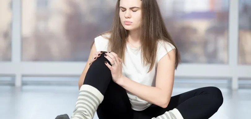Young woman holding sore knee from diabetics legs discomfort