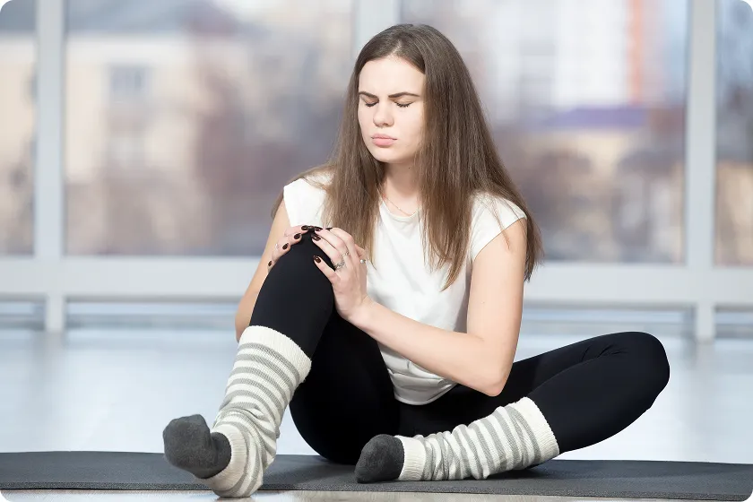 Young woman holding sore knee from diabetics legs discomfort