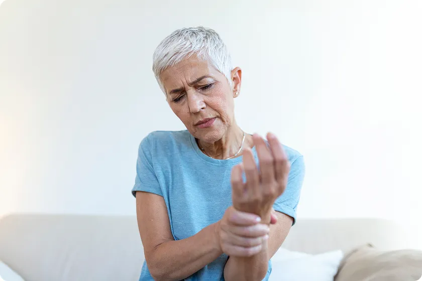 Older woman holding wrist with diabetic cheiroarthropathy, hand stiffness