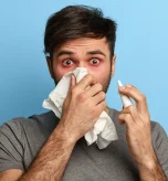 2 Man using nasal spray for relief from dust allergy and dust mite symptoms.