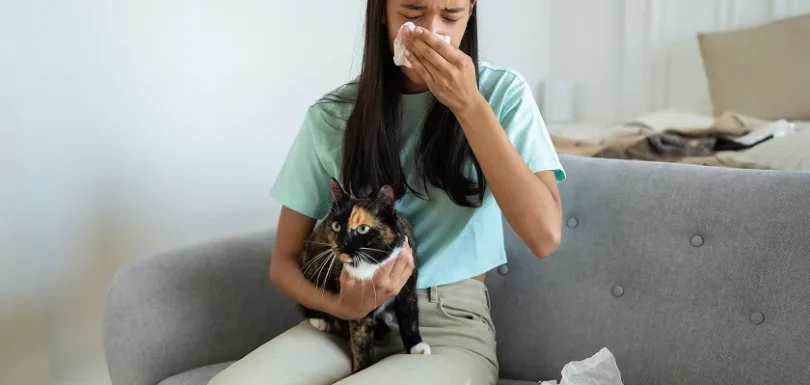 Woman holding cat experiencing symptoms for cat allergy treatment at home