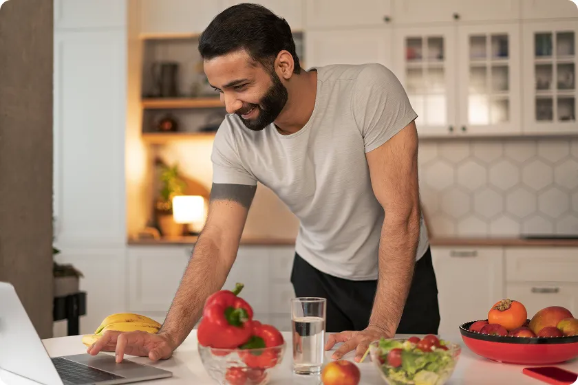 Smiling man checking a healthy diet plan for a sports person on his laptop.