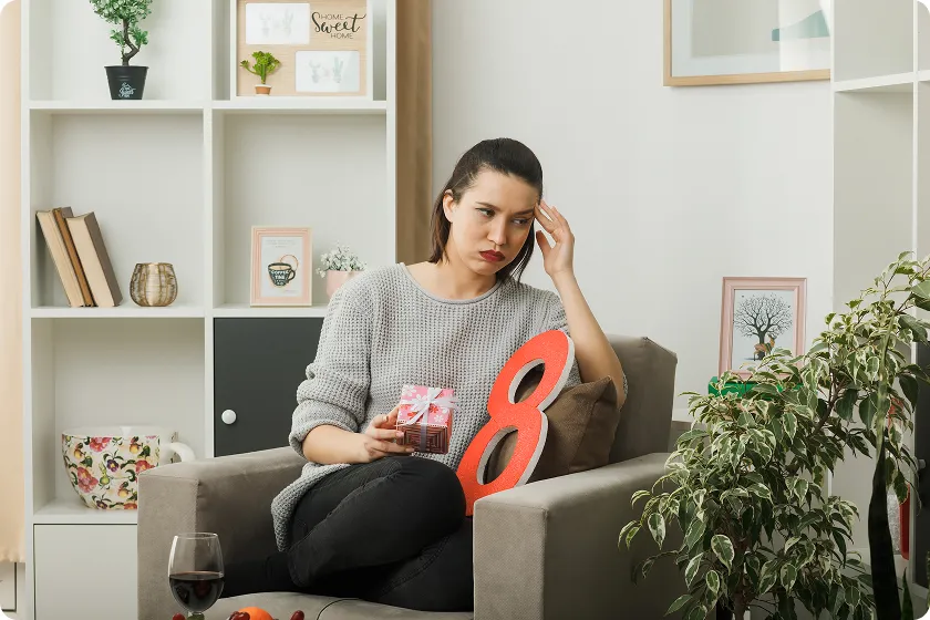 A stressed woman experiencing menstrual irregularities perimenopause symptoms on an armchair.