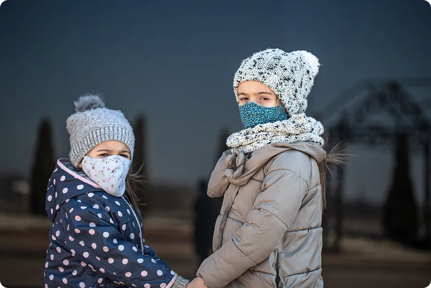 Children wearing hats and masks outside to reduce winter allergies exposure.