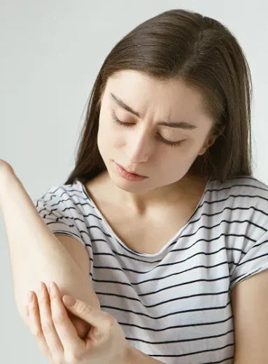 Woman scratching arm due to allergic reaction to wasp sting, yellow jacket allergy possible.