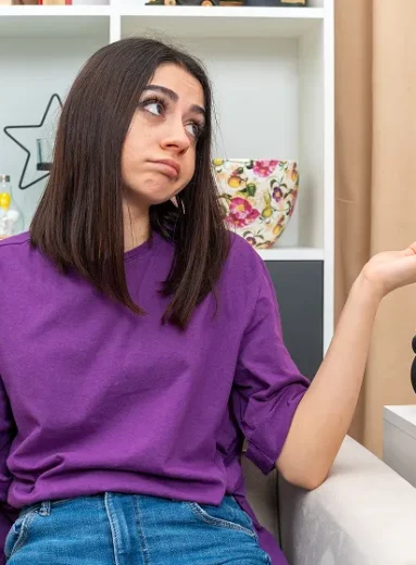 Confused woman sitting next to a clock tracking irregular periods during perimenopause.