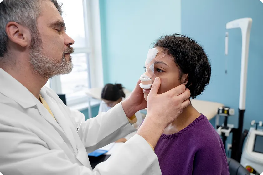 Doctor examines a patient with a bandaged nose understanding what causes nasal polyps.