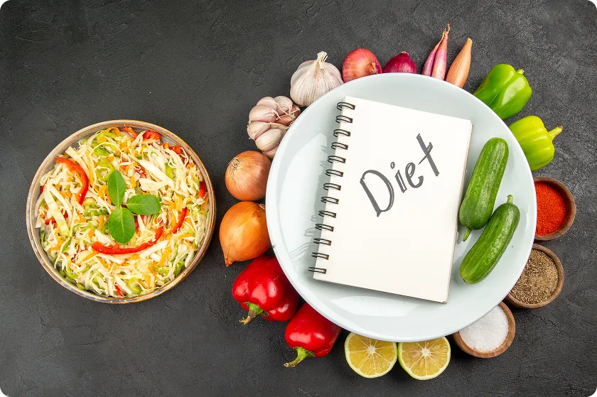 Top-down view of fresh vegetables surrounding a notepad showcasing a strict diverticulosis diet.