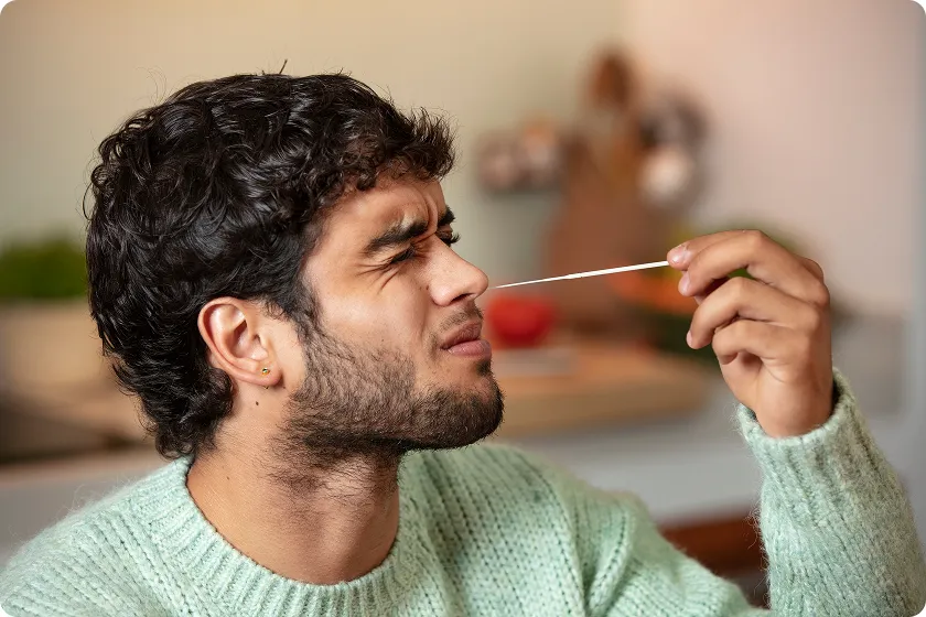 Man grimacing while taking a nasal swab test to identify what causes nasal polyps.
