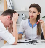 Woman wearing headset presses temples while exploring chronic migraine treatment options.