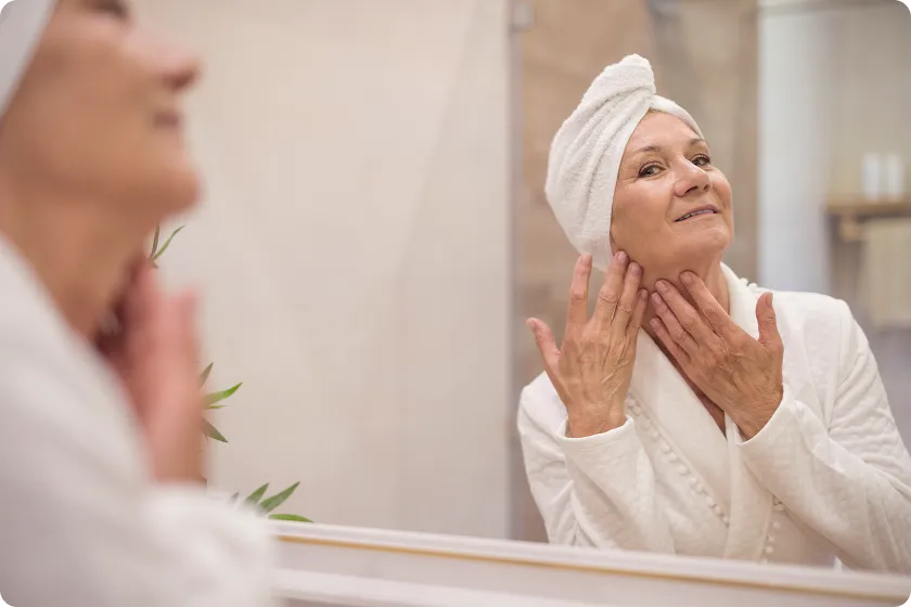 Red-haired woman uses facial roller in an anti-aging skincare routine.