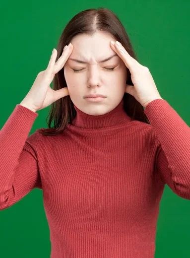 2 Young woman holds temples, challenging migraine myths and migraine misconceptions.