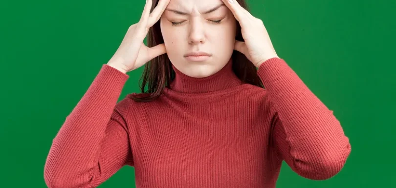 Young woman holds temples, challenging migraine myths and migraine misconceptions.