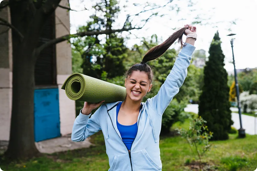 Woman carrying yoga mat after tension relieving exercises outdoors