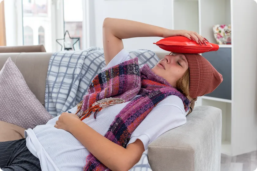 Sick woman resting on couch seeking natural constipation relief with heat therapy