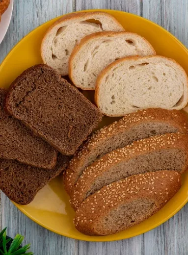 4_4_11zon Yellow plate filled with various baked goods illustrating typical carbs in bread options.